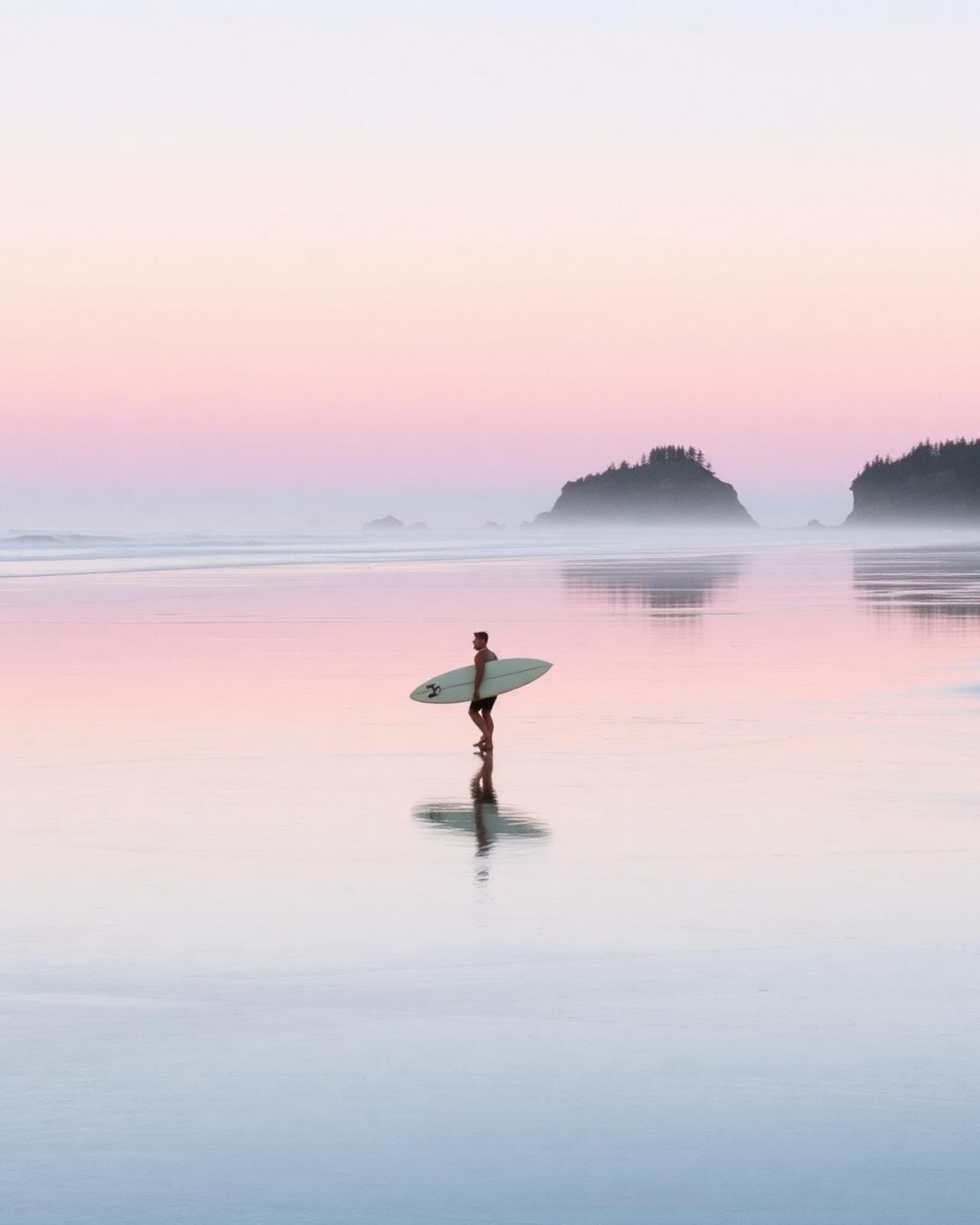 Surfer walking on Chesterman Beach at dusk